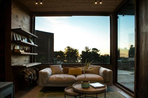 a living room with a couch and a large window at Cuarzo Lodge in Pichilemu