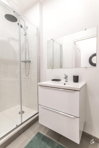 une salle de bain blanche avec un lavabo et une douche dans l'établissement COSY COMEDIE, à Bourg-en-Bresse