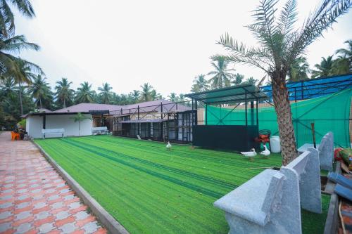 a grassy yard with a building and a palm tree at Royal Destiny Resort in Malaiyāndipattanam