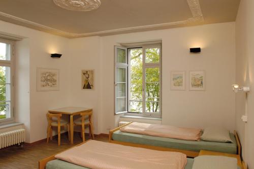 a room with two beds and a table and windows at Richterswil Youth Hostel in Richterswil