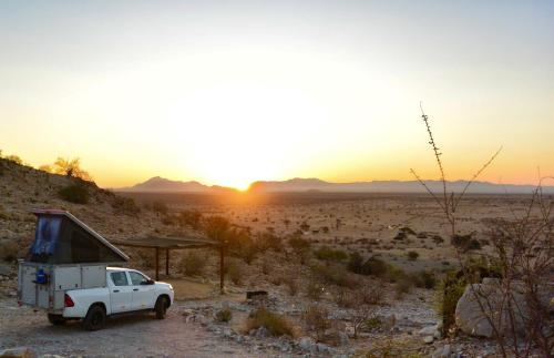 a white truck parked in the desert at sunset at Camp Gecko - PRIVATE NATURE RESERVE; TENTED CAMP AND CAMPSITE in Solitaire