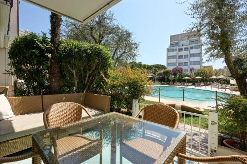 a patio with a glass table and chairs next to a pool at Villa Carlotta Jesolo Lido in Lido di Jesolo