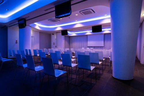 a conference room with blue chairs and a podium at A Point Porto Ercole Resort & Spa in Porto Ercole