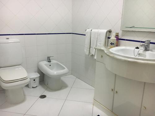 uma casa de banho branca com um WC e um lavatório em Apartamento T1 com Piscina e Vista mar - PRAIA DA ROCHA Portimão em Portimão