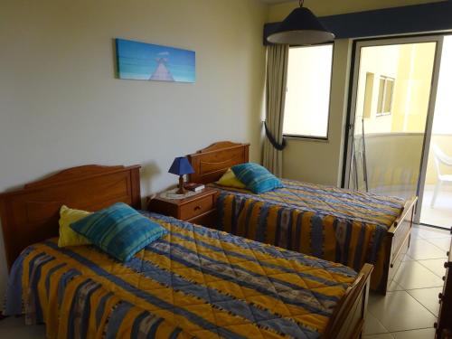 um quarto de hotel com duas camas e uma janela em Apartamento T1 com Piscina e Vista mar - PRAIA DA ROCHA Portimão em Portimão
