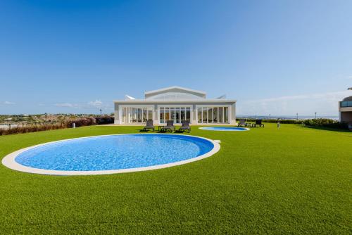 a house with a pool in the middle of a grass field at Boavista Golf and Spa Resort - Bayview in Lagos
