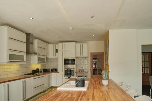 a kitchen with white cabinets and a wooden counter top at Modern Spacious House - Sleeps 16, Free Parking, Sun Terrace in Attleborough