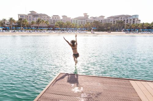 a woman jumping into the water at the beach at Four Seasons Resort Dubai at Jumeirah Beach in Dubai
