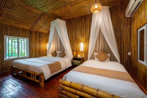 two beds in a room with wooden walls at An's Eco Garden Resort in Ninh Binh