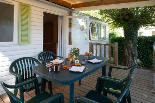 une table bleue avec quatre chaises sur une terrasse couverte dans l'établissement Camping du Bournat, au Bugue