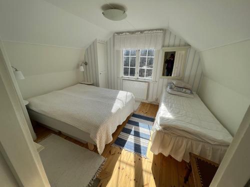 a small bedroom with two beds and a window at Tutviksvägen 35 in Vendelsö