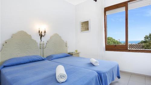 una camera da letto con un letto con lenzuola blu e una finestra di Villa Care 1 - Llafranc a Llafranc