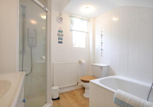 a bathroom with a tub and a toilet and a shower at Primrose Cottage in Gullane