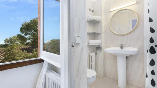 un bagno con lavandino, WC e finestra di Villa Care 1 - Llafranc a Llafranc