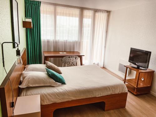 una habitación de hotel con una cama y un televisor en UXCO Grenad'inn, en Burdeos