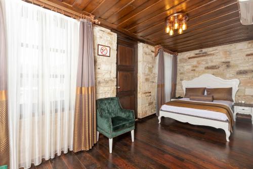 a bedroom with a bed and a green chair at Marina Foça Hotel in Foça