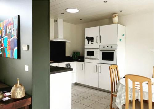 a kitchen with white cabinets and a table in it at Gite Botiga in Saint-Jean-le-Vieux