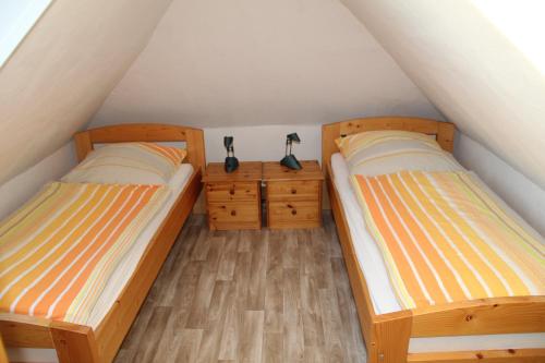 2 Betten in einem kleinen Zimmer mit Holzböden in der Unterkunft Haus Mühlenblick in Neuharlingersiel