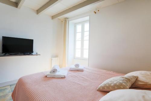 een slaapkamer met een bed met handdoeken en een televisie bij Maison de village Casserone pour 4 personnes in Ars-en-Ré