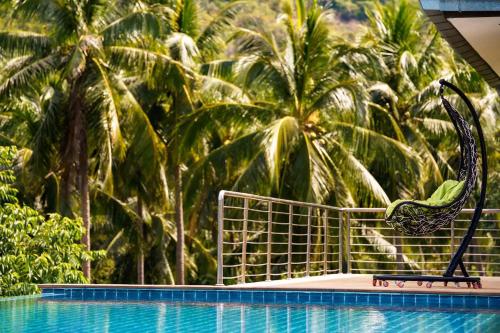 a swimming pool with a dinosaur chair next to palm trees at Villa E in Taling Ngam Beach