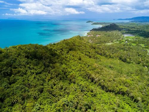 an aerial view of a forested hill with the ocean at Villa E in Taling Ngam Beach