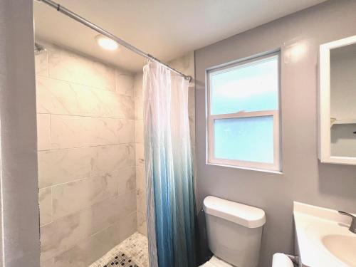 a bathroom with a shower and a toilet and a window at WHOLE Family - Oak Park in Sacramento
