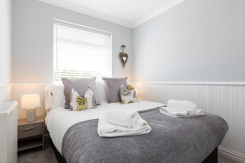 a white bedroom with a bed with towels on it at Curlew - 3 Bedrooms Wi-Fi, Parking, Contractors in Thornton