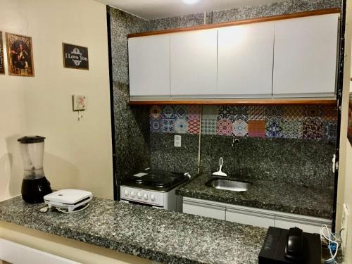 cocina con encimera con fogones y armarios blancos en Atlantico Flat, en Fortaleza