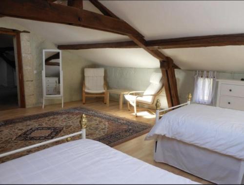 una camera con 2 letti bianchi e una sedia di Closerie Les Roches - Charming and spacious 2 bedroom cottage a Bouillé-Loretz