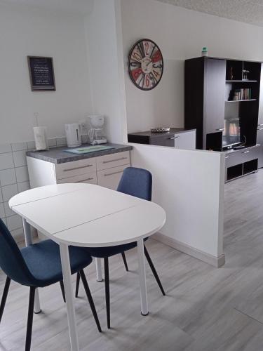 a kitchen with a white table and chairs and a clock at Les tilleuls in Vittel