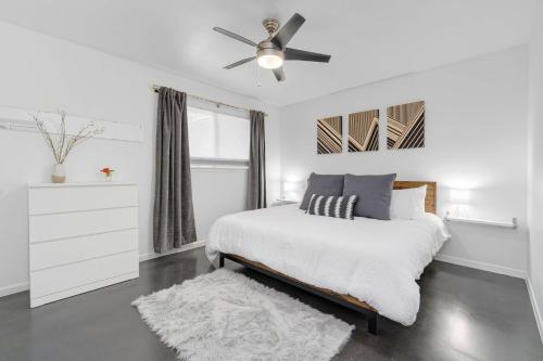 a white bedroom with a bed and a ceiling fan at The Avocado Door - A Mid-Century Modern Gem ~ Near SoCo ~ Fenced yard ~ Corner lot in Austin