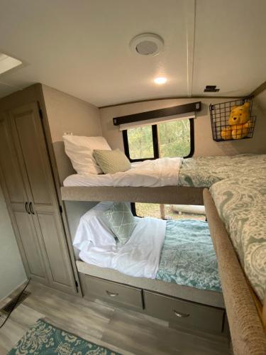 een kleine kamer met 2 stapelbedden en een raam bij Cozy RV Experience w/POOL+SPA Near Lake Conroe in Willis