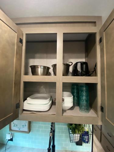a cabinet with plates and pots and pans in it at Cozy RV Experience w/POOL+SPA Near Lake Conroe in Willis