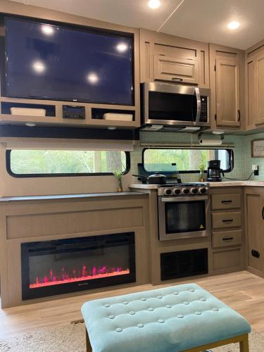 a kitchen with a fireplace with a tv above it at Cozy RV Experience w/POOL+SPA Near Lake Conroe in Willis