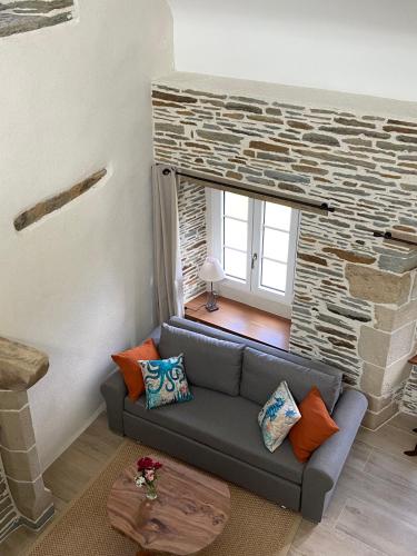 a living room with a couch and a stone wall at Domaine de Kerdavid - Chambres d'hôtes à Remungol in Évellys