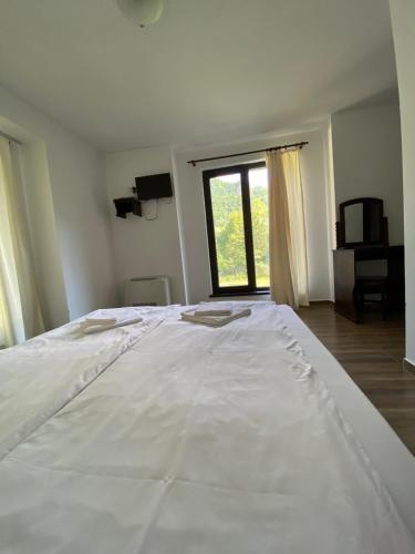 a large white bed in a room with a window at Complex Magic of the Rhodopes in Bachkovo
