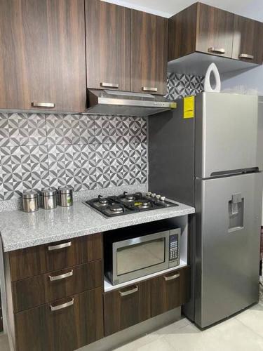 a kitchen with a stove and a refrigerator at Centro histórico Downtown Depto completo alberca climatizada AC parking free seguridad 24 hras in Guadalajara