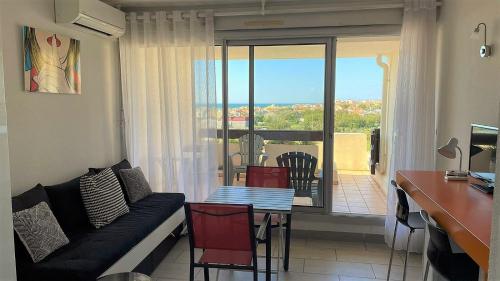 un salon avec un canapé et une table avec vue dans l'établissement Appartement Village Naturiste Tornado, au Cap d'Agde