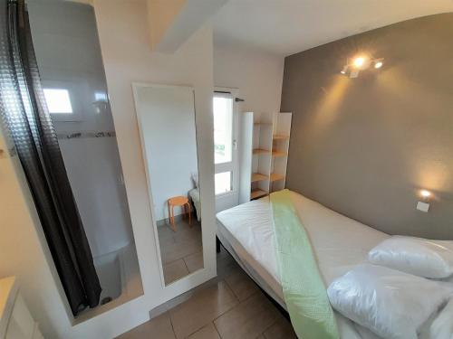 ein kleines Zimmer mit 2 Betten und einem Spiegel in der Unterkunft Appartement Village Naturiste Tornado in Cap d'Agde