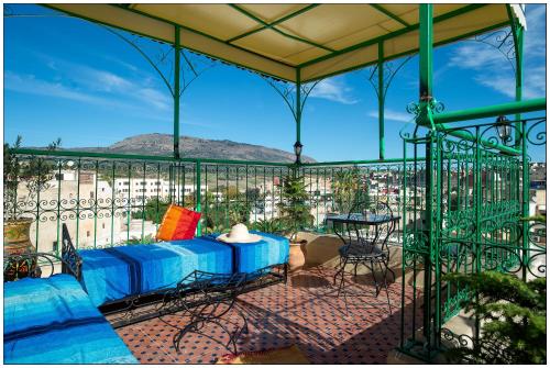 a balcony with a blue couch and a table and chairs at Riad Fés blida in Fès