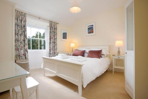 a white bedroom with a white bed and a window at 5 Lowfield, Ambleside in Ambleside