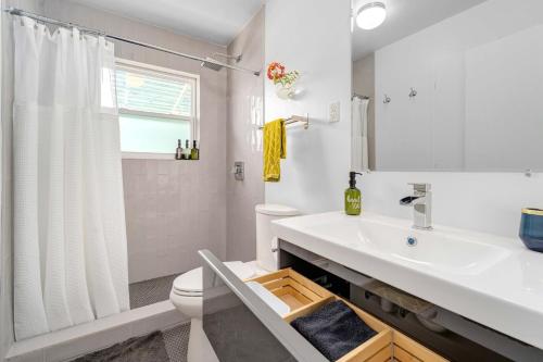 a white bathroom with a sink and a toilet at The Avocado Door - A Mid-Century Modern Gem ~ Near SoCo ~ Fenced yard ~ Corner lot in Austin