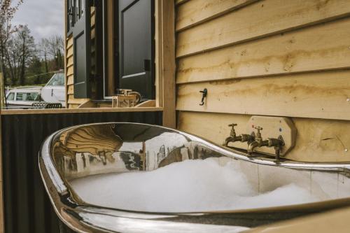 Saltford的住宿－Island Hut - Outdoor bath tub, firepit and water equipment，坐在雪地建筑前面的椅子