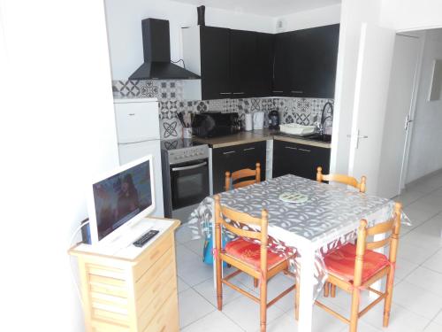 une cuisine avec une table et des chaises et une télévision dans l'établissement IPANEMA - Canet en Roussillon - Vue mer - 41 m², à Canet