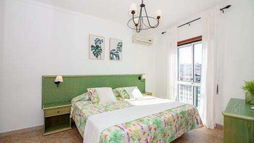 a bedroom with a bed with a green headboard and a window at Altura Vacations T2, Algarve in Altura