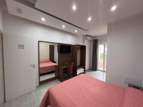 a bedroom with a bed and a desk and a television at Hotel La Mela in Varcaturo