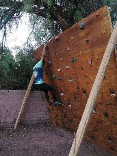 a person is climbing on a climbing wall at CaminAndes Hostal in San Pedro de Atacama