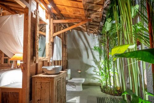 a bathroom with a toilet and some plants at Bajalo Cottage Canggu in Canggu