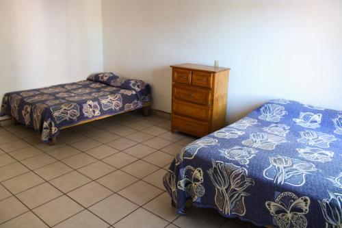 une chambre avec deux lits et une commode en bois dans l'établissement C2 Alberca privada a 5 min de la playa, en planta alta, à La Peñita de Jaltemba