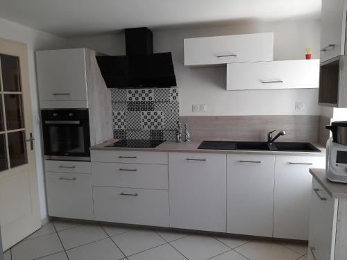 a white kitchen with white cabinets and a sink at Les Trémières in Le Thou